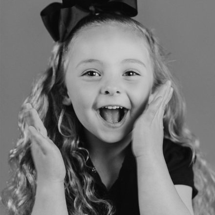 joyful black and white school portrait of a girl with a black bow in Denver